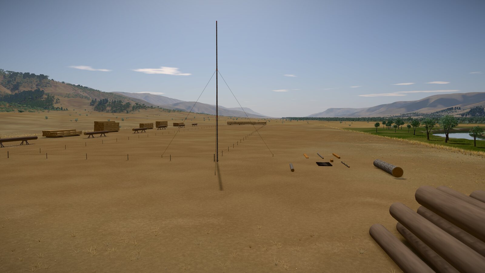 The level building site, staked out at the ark's real size: a tall marked pole at one corner held by guy ropes, stakes along the sides, timber stacked beyond, and hills behind.